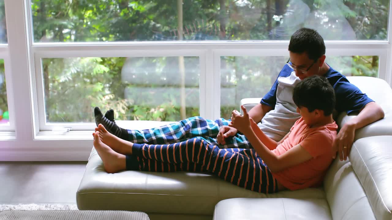 padre e hijo usando teléfono móvil en la sala de estar 4k