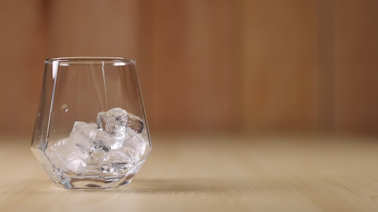 얼음 큐브가 테이블 위의 유리잔에 떨어집니다.