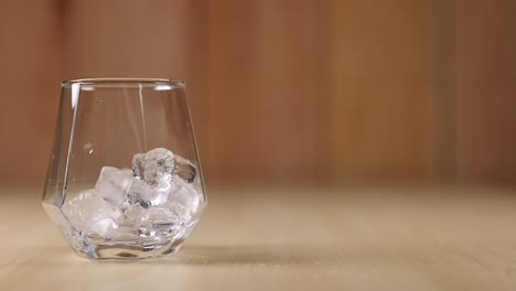 cubos de hielo cayendo en un vaso en la mesa