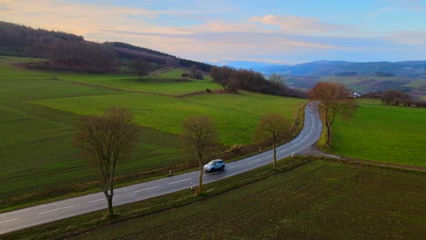 Aerial-View-of-Bruchhausen-an-den-Steinen-Surrounded-by-Beautiful-Landscape-with-Cars-Driving-on-a-Small-Road-During-Early-Morning-Light