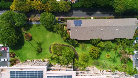green gardens and buildings with solar panels on the roof, overhead aerial view moving to the right.