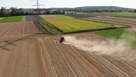 Luftaufnahme-Hinter-Einem-Traktor,-Der-Auf-Einem-Windigen-Feld-Staub-Erzeugt