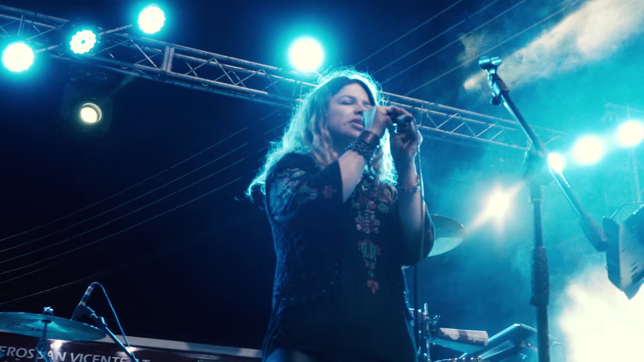 Close-up gerak lambat penyanyi rock wanita, menyanyikan lagu di konser luar ruangan