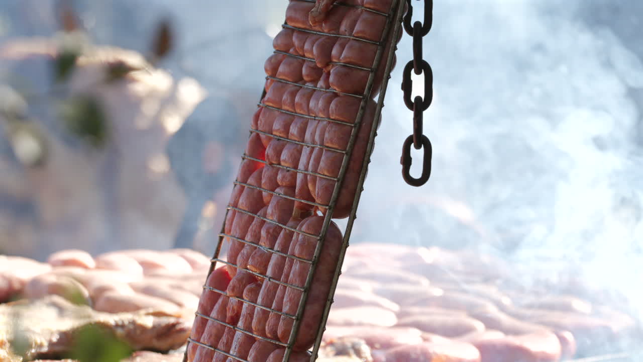 Grilled sausage barbecue with burning and smoking firewood, close up