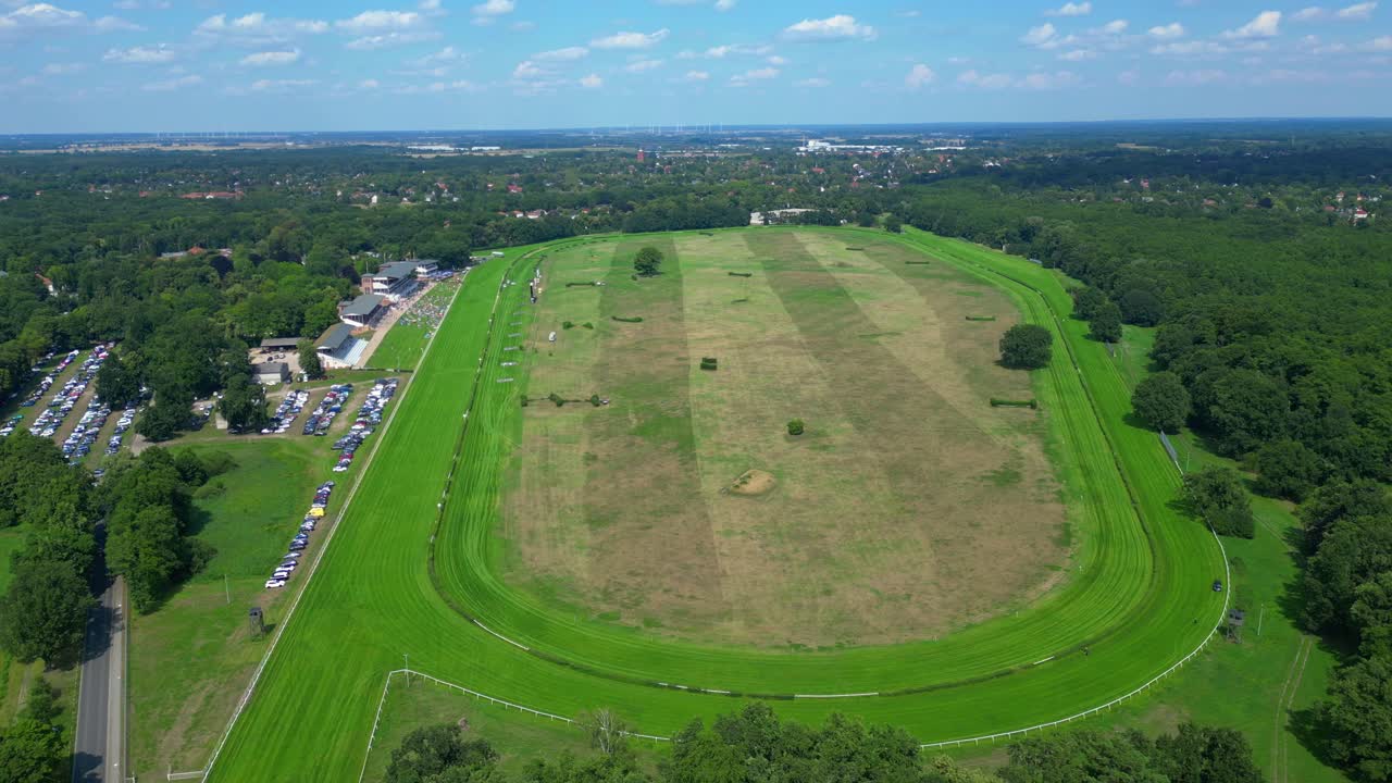 Horse gallop racecourse near a forest in Germany, parking lot visible. Best aerial view flight wide orbit overview drone