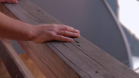 dos manos masculinas en una viga de madera de la baranda