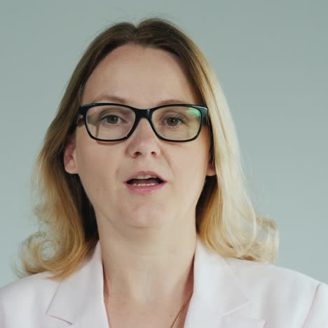 mujer con gafas dice una lección sobre un fondo blanco