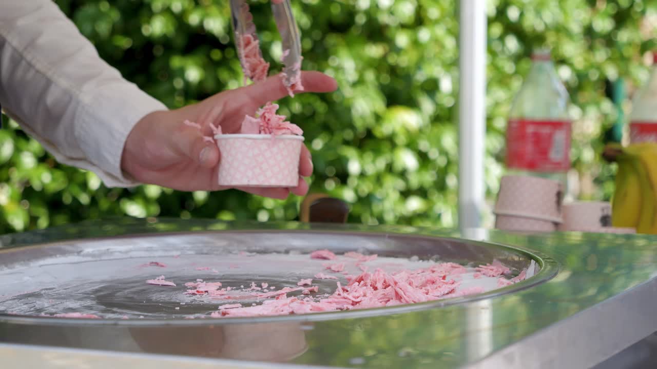 Slowmotion-optagelse af en isrulle-sælger, der serverer jordbæris