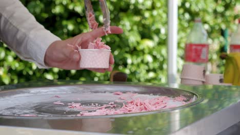 slow motion shot of a rolled icecream vendor serving strawberry icecream