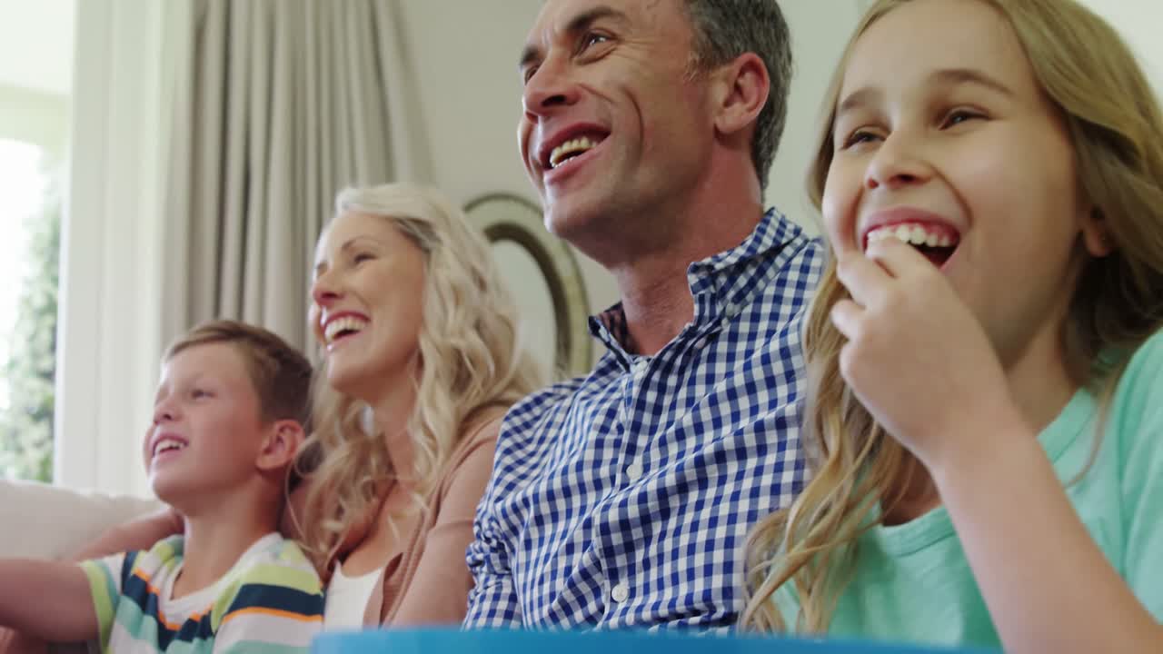 행복 한 가족 이 거실 에서 함께 텔레비전 을 보고 있다