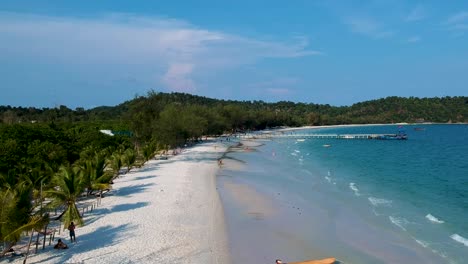 aerial landscape shot of turquoise blue sea with white sand beach and wooden pier