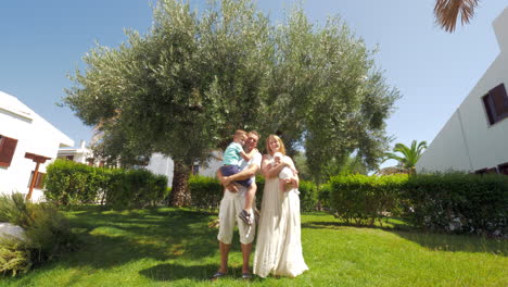 parents with children near olive tree in green garden
