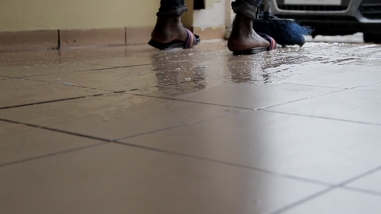 ver el piso hombre afroamericano limpiando el piso con agua y jabón para protegerlo de bacterias no deseadas y virus peligrosos