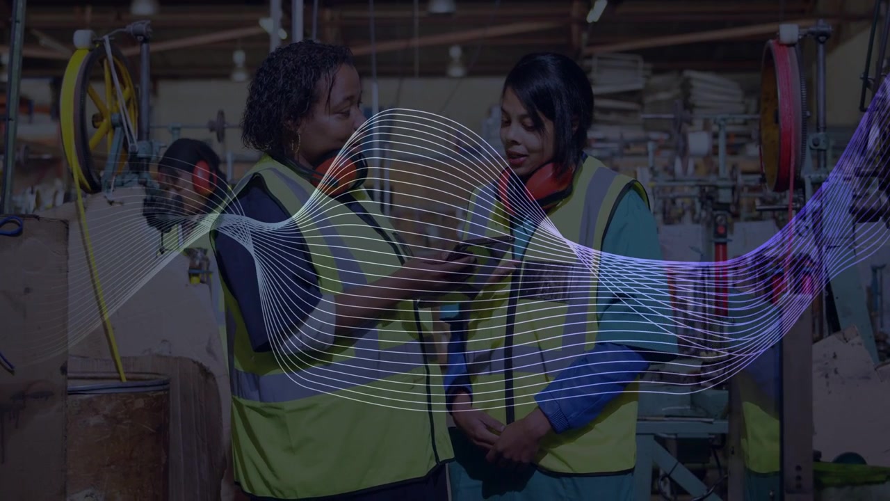 Animated wave sweeping across frame, mentor explaining tablet to peer, revealing screen in factory