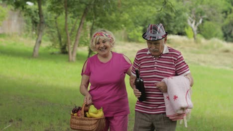 family weekend picnic. active senior old caucasian couple in park. husband and wife walk together