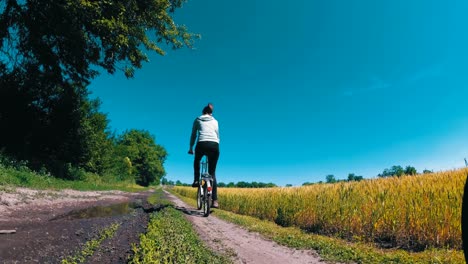 young woman riding vintage bicycle along a rural road in a village