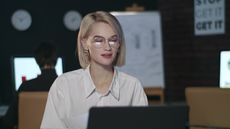 Donna d'affari felice che esamina un rapporto finanziario in un ufficio buio.