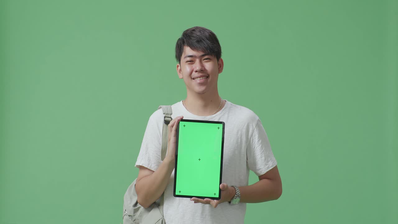 초록색 화면을 가진 태블릿을 들고 있는 미소 짓는 학생