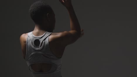 vista trasera de una joven vestida con ropa de gimnasia calentándose para el ejercicio 1