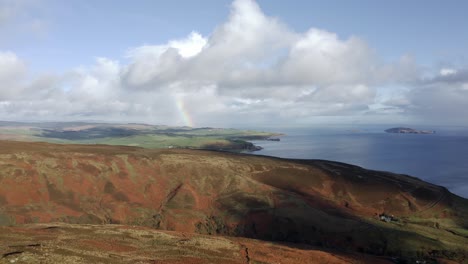 drone shot rising over hills and the sea in the highlands of scotland