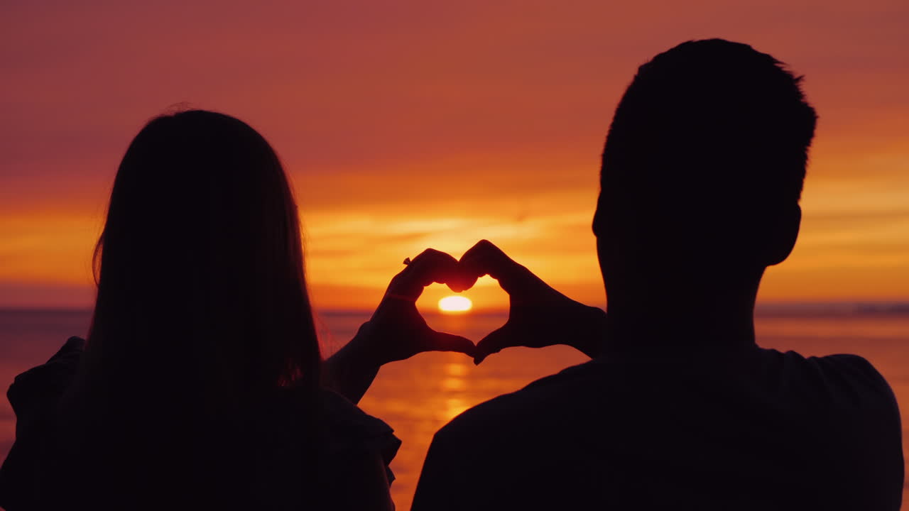 Silhouettes Of A Young Couple Hands Show The Shape Of The Heart Against The  Backdrop Of The Sunset O Free Stock Video Footage Download Clips Family