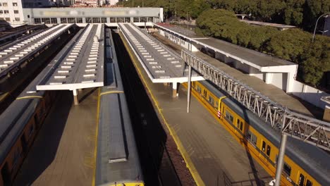 birds eye forward view of yellow train arriving at federico lacroze station of buenos aires in argentina