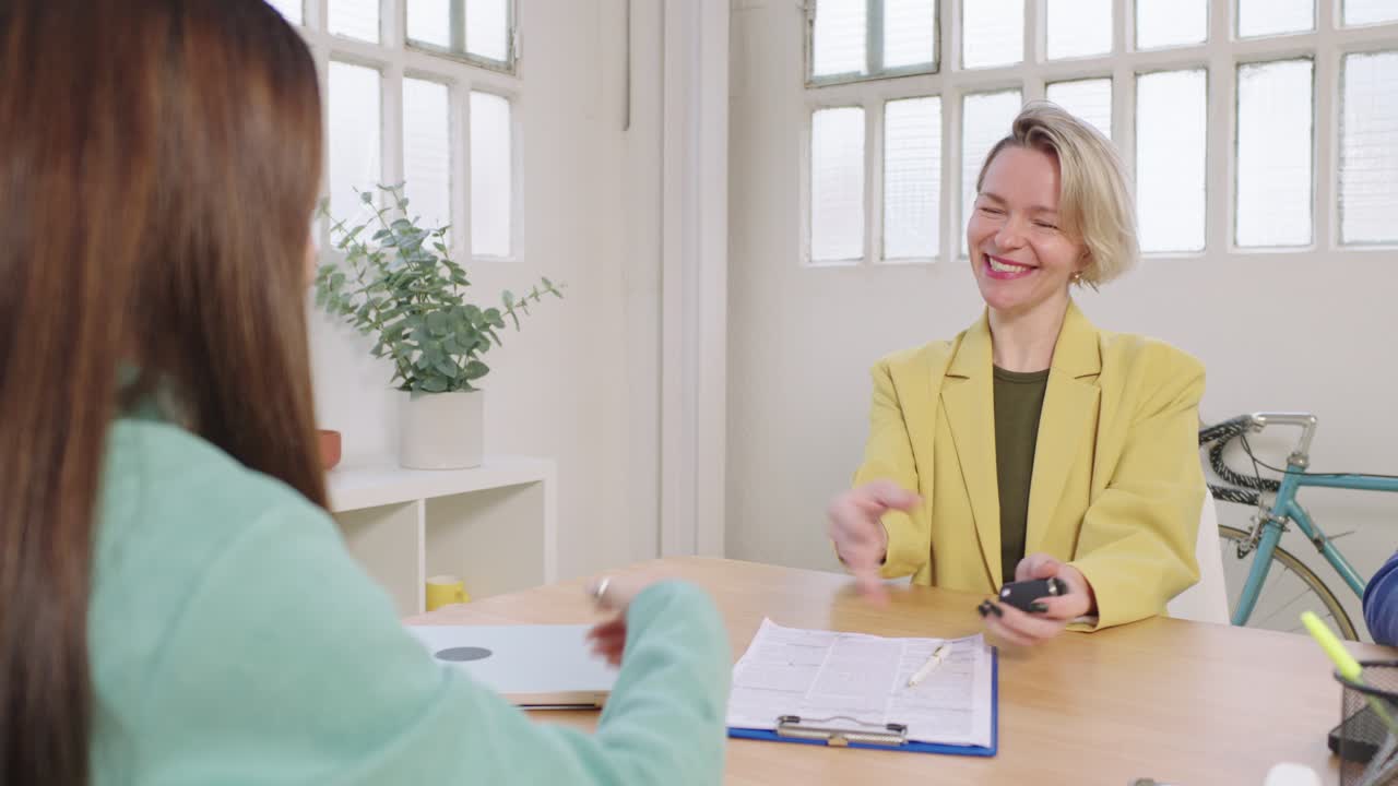 Businesswomen negotiating and shaking hands in an office setting