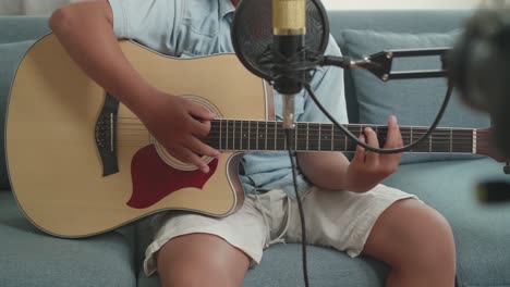 boy playing acoustic guitar at home