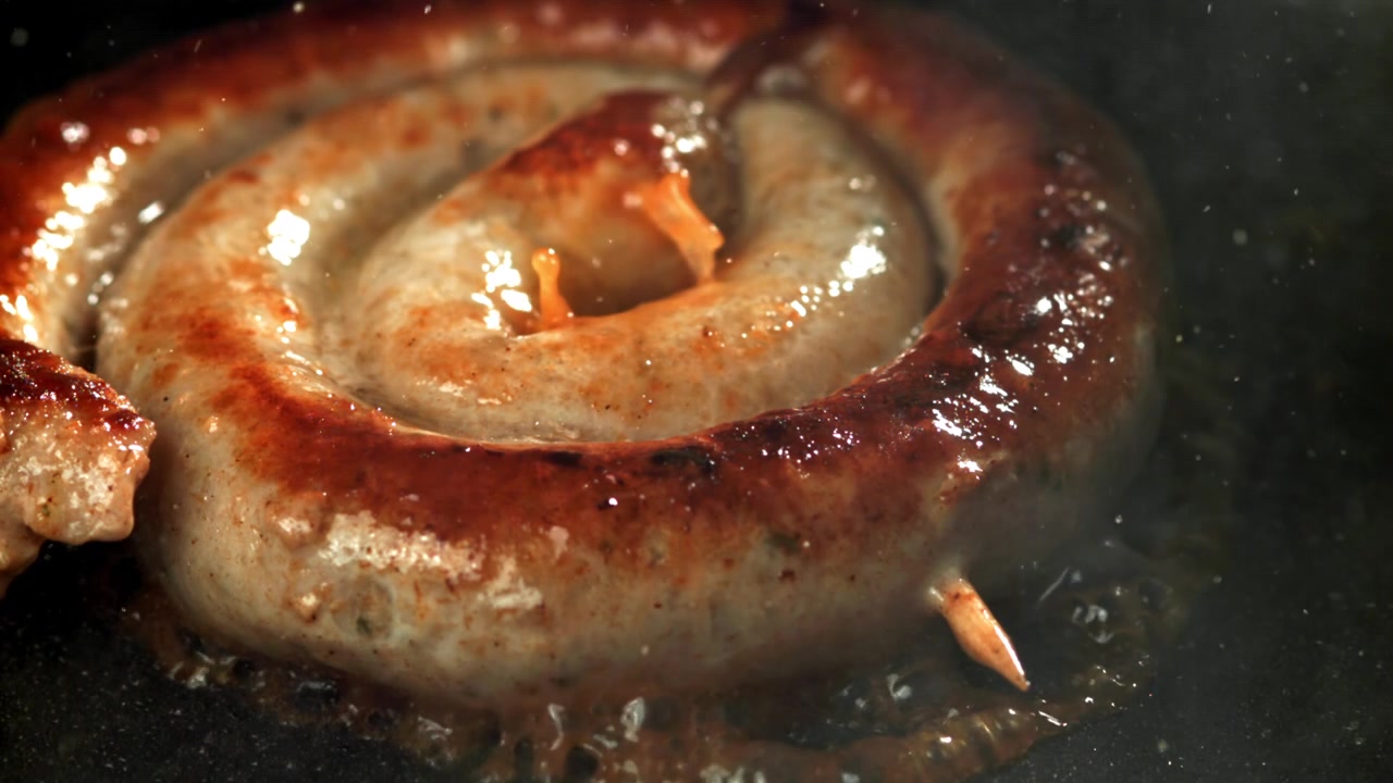 Närbild på en läcker korvspiral som steks i en het panna