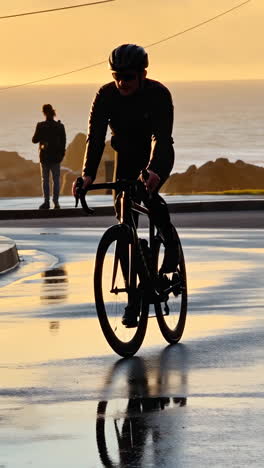 Cyclist Silhouetted by Golden Sunset on a Wet Coastal Road