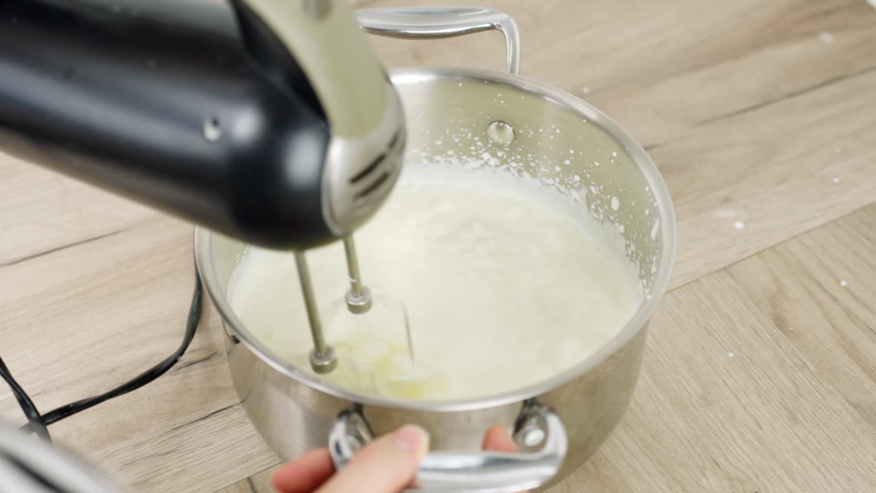Process of baking a cake, whipping cream in a bowl with a hand mixer