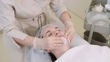 cosmetologist doing face treatment and applying face mask