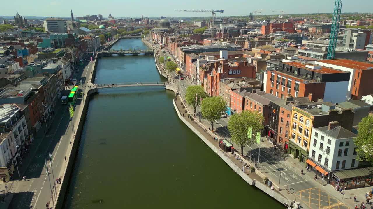 Overhead, advancing aerial video of the Ha'penny Bridge and River Liffey in Dublin City Centre, Dublin, Ireland on a bright and sunny day. Filmed in 4K, 60FPS and with Rec709 color.