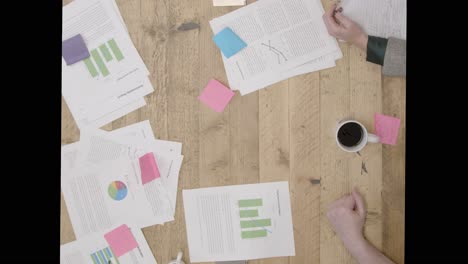 Overhead-View-Colleagues-At-Table-Stacking-Hands