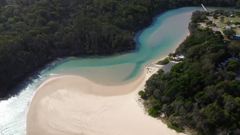 Cinematic-revealing-drone-shot-of-the-Korogoro-Creek-with-with-tropical-mountains-in-the-distance-at-Hat-Head-New-South-Wales,-Australia