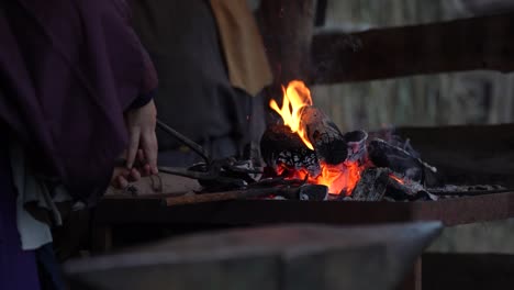 blacksmith heating iron in the forge, shaping and forming it with a hammer, skilled craftsman for traditional handcrafted tools