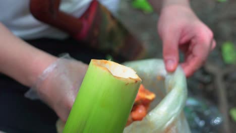 campers stuff glazed raw meat and vegetables into the bamboo to cook with fire