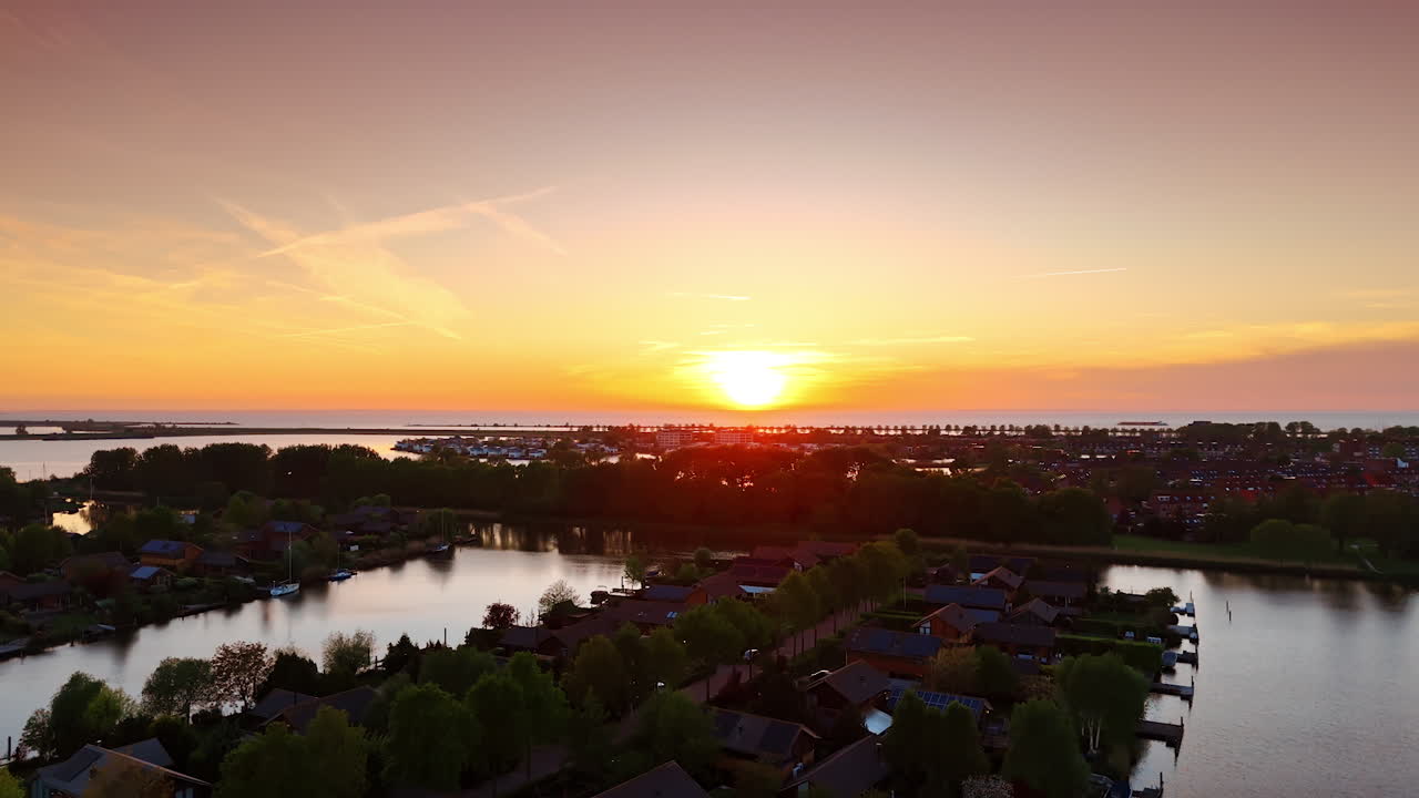 Stunning sunset over the vast waterscape. Silhouette of a village located on the water at foreground.