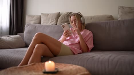 mujer relajándose en el sofá con auriculares y teléfono