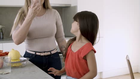 una niña divertida cocinando con su madre.