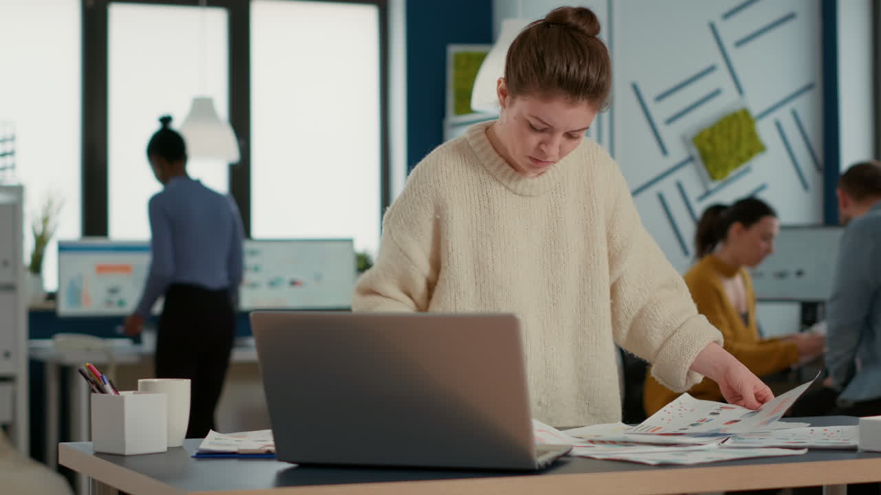 Ritratto di dipendente di startup concentrato che guarda laptop e grafici confrontando le statistiche di vendita