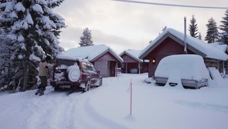 man opening the car and let his dog gets off the trunk in a snow-covered country village