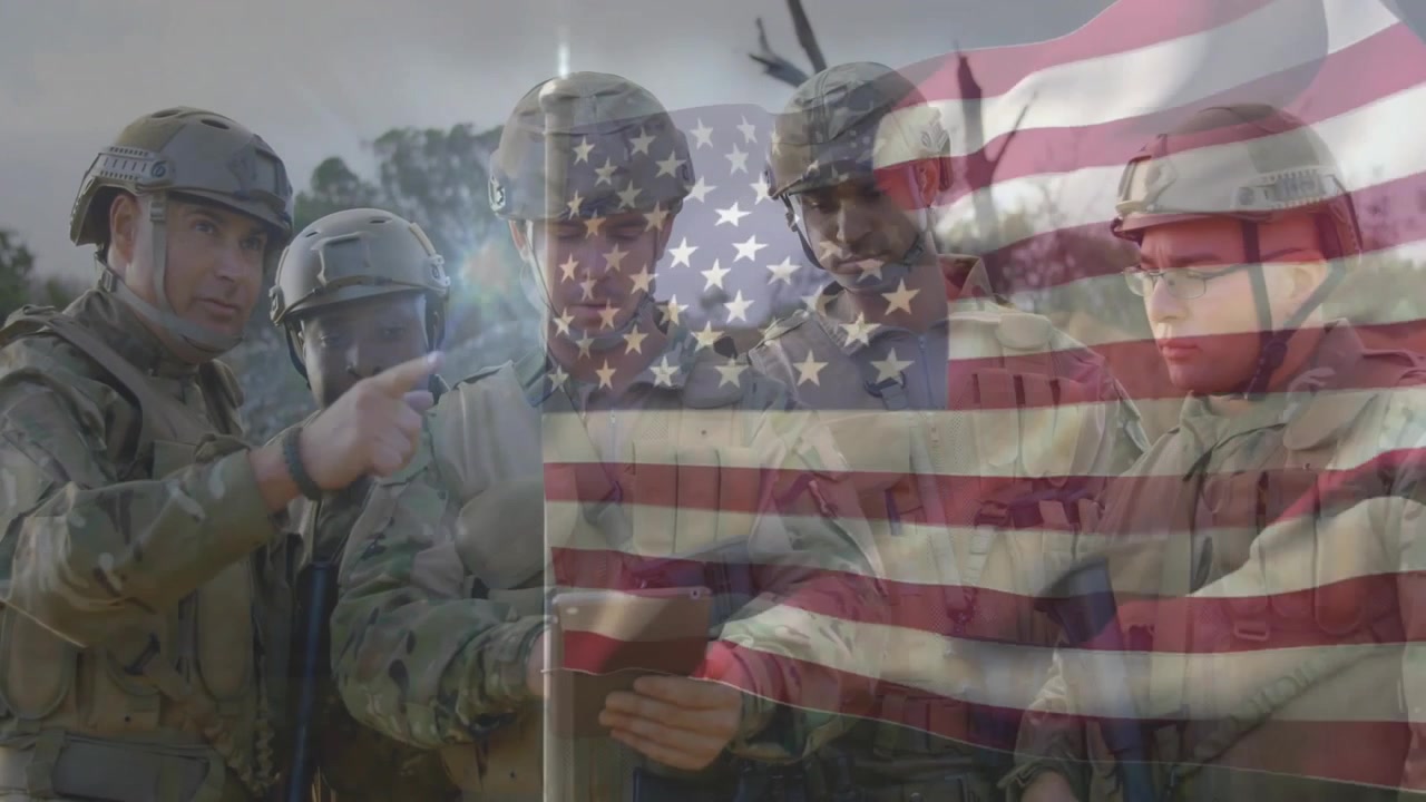 Squadra militare che si riunisce attorno a un tablet dopo una sovrapposizione della bandiera americana, puntando verso la linea del bosco.
