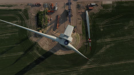 Birds-eye-view-of-electricity-generator-on-tall-pole.-Construction-of-wind-power-plant.-Green-energy,-ecology-and-carbon-footprint-reduction-concept