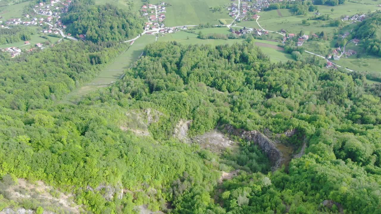 Green lush mountainside toward country roads and small town, Slovenia, aerial approach