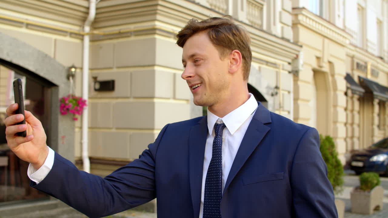 retrato de un hombre alegre haciendo una llamada de video por teléfono móvil al aire libre