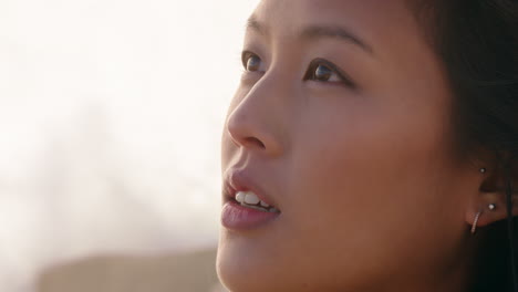 close up portrait beautiful asian woman enjoying freedom exploring wanderlust feeling relaxed on seaside contemplating spirituality at sunset with wind blowing hair