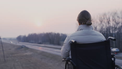 Vista-Trasera-De-Una-Mujer-Discapacitada-En-Silla-De-Ruedas-Grabando-El-Paisaje-Al-Atardecer