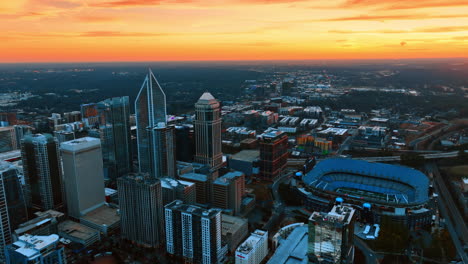 descending above the panorama of a metropolis at dusk. orange sky above the scenery of charlotte, nc, usa at sunset
