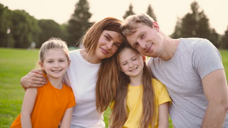 porträt einer glücklichen familie, die lächelt und in die kamera schaut, während sie zeit miteinander im park verbringt 2